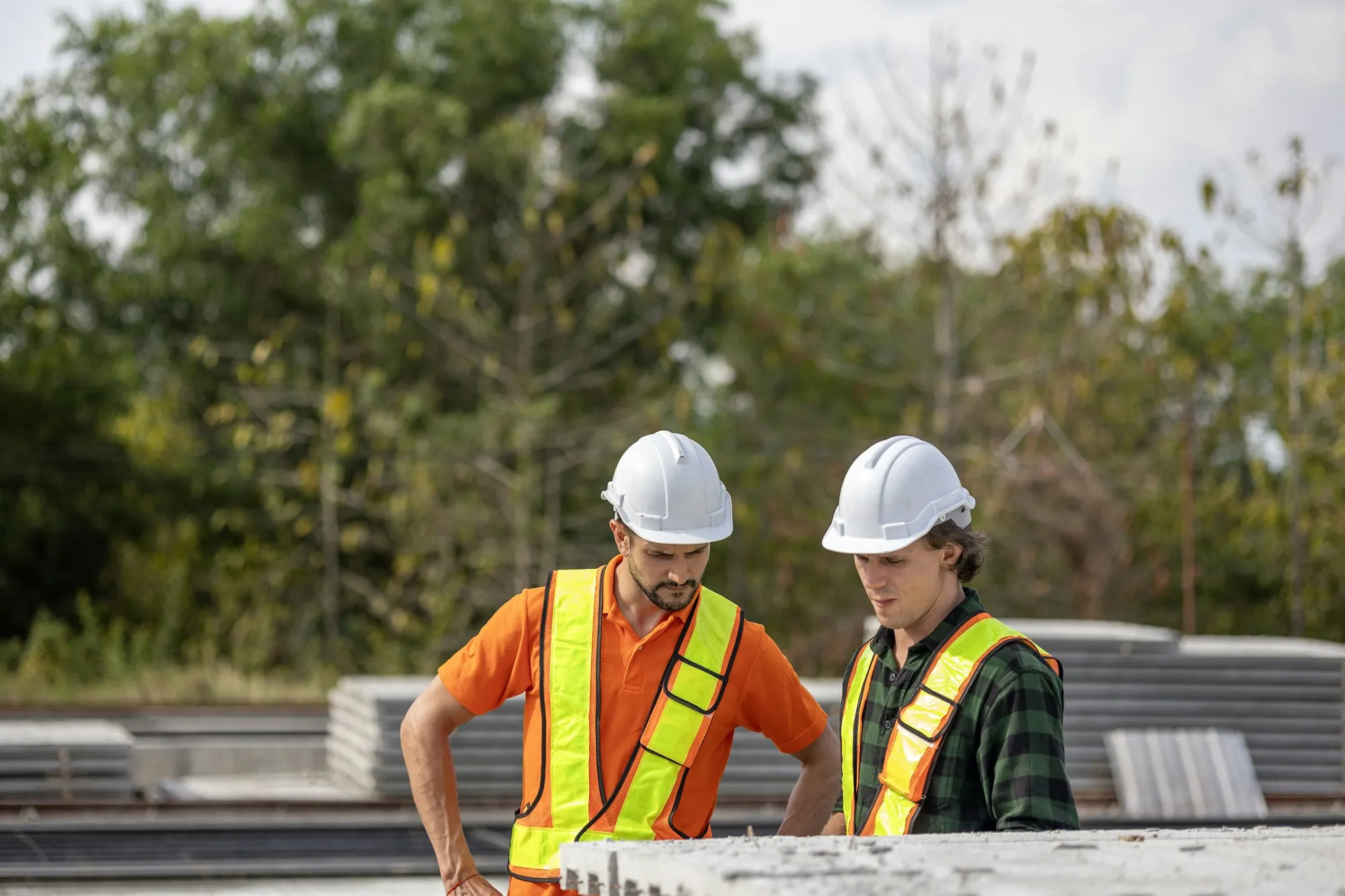 Two workers in hard hats reviewing plans at a job site