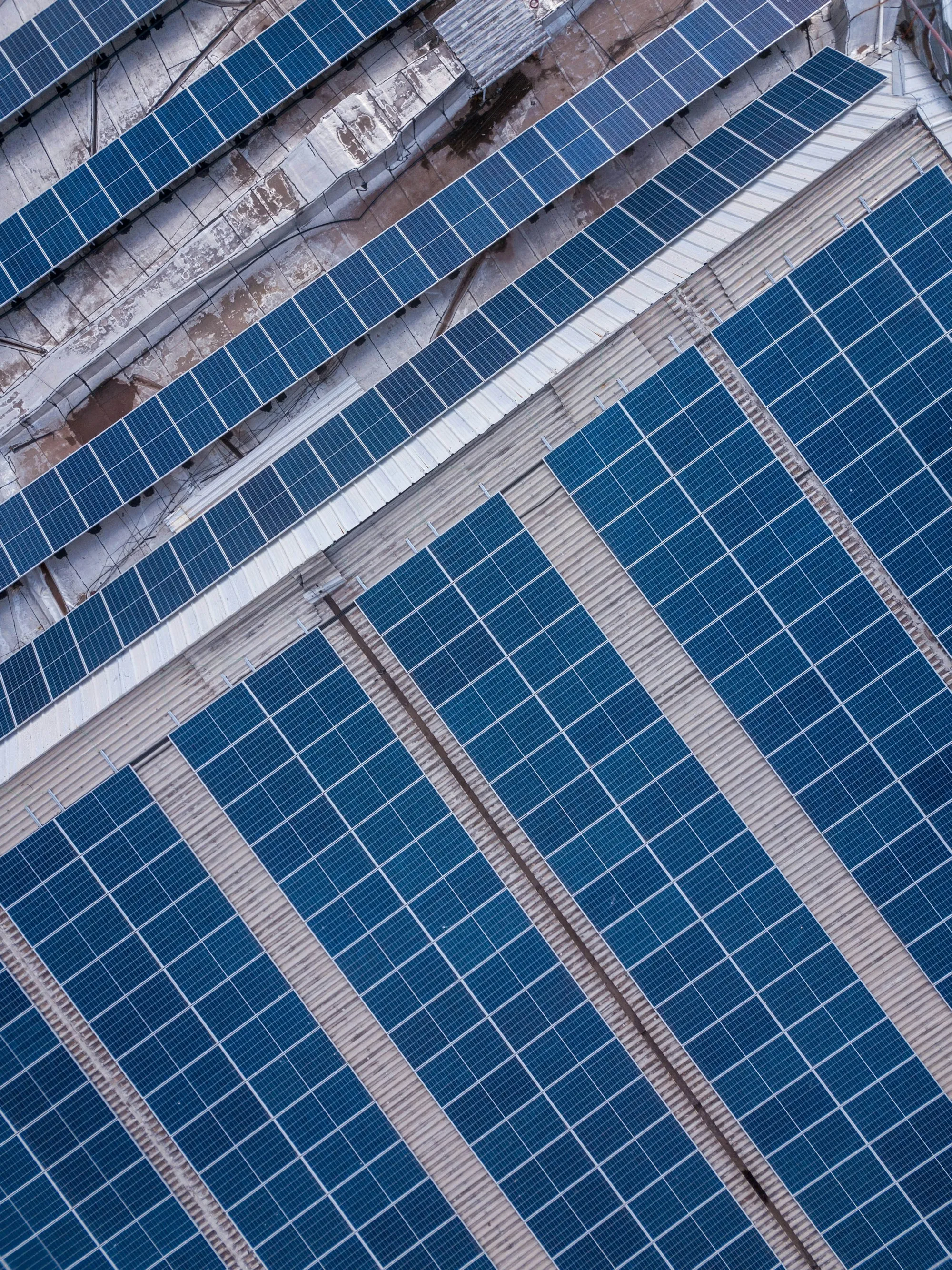 Diagonal rows of blue solar panels seen from above, the kind of array that needs new mount flashing after a Crestwood reroof